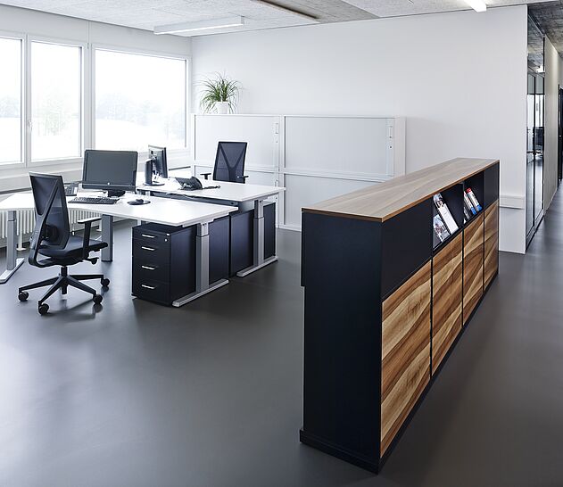 Zwei OPTIMO Arbeitsplätze mit je einem Arbeitstisch und Bürodrehstuhl.